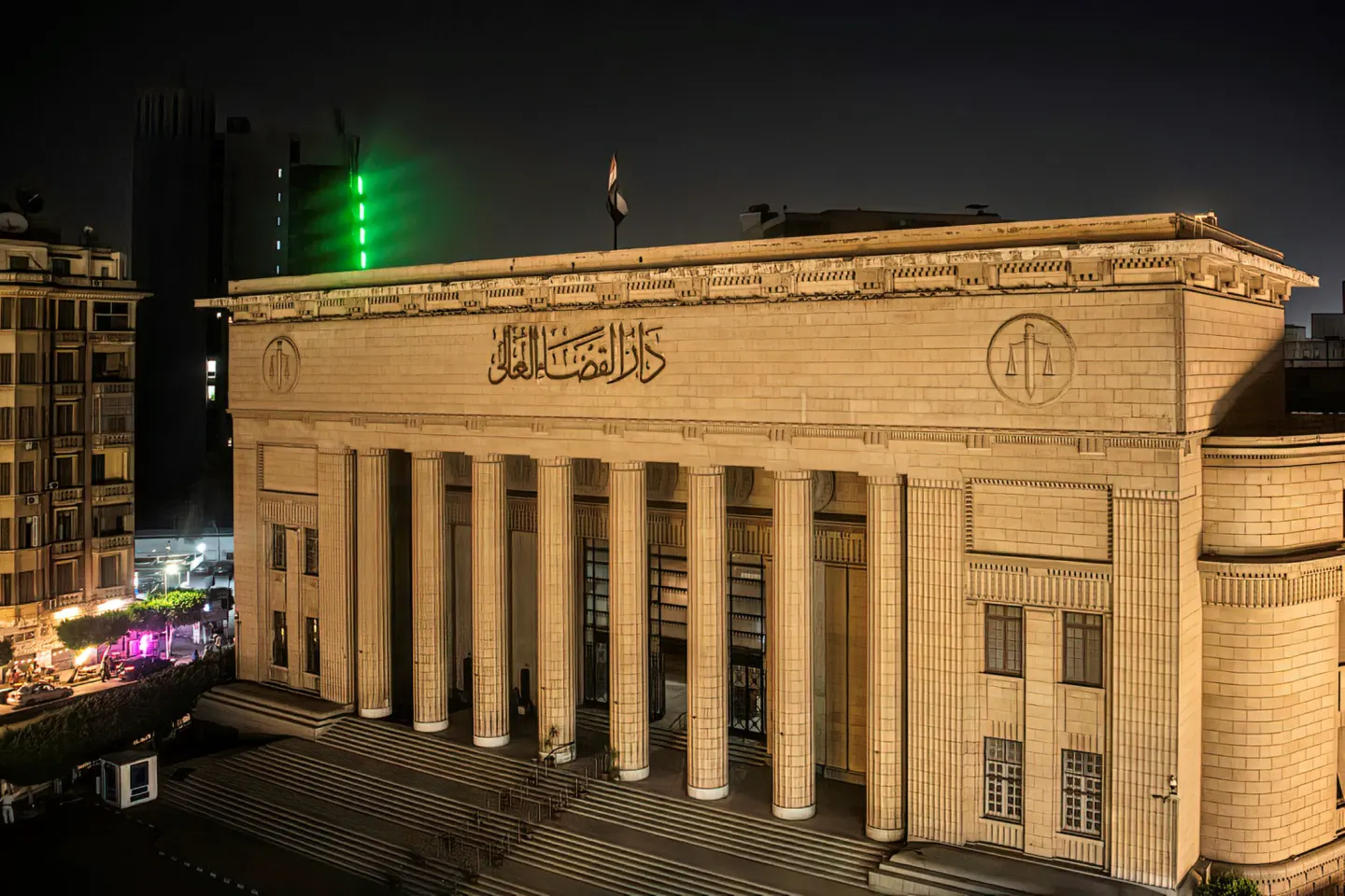 Illuminated neoclassical courthouse in Cairo at night, its columned entrance lit gold